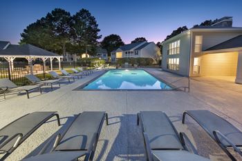 a swimming pool with lounge chairs around it at night